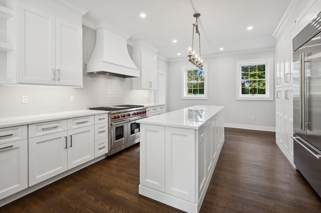 kitchen with high end appliances, premium range hood, pendant lighting, a kitchen island, and white cabinetry