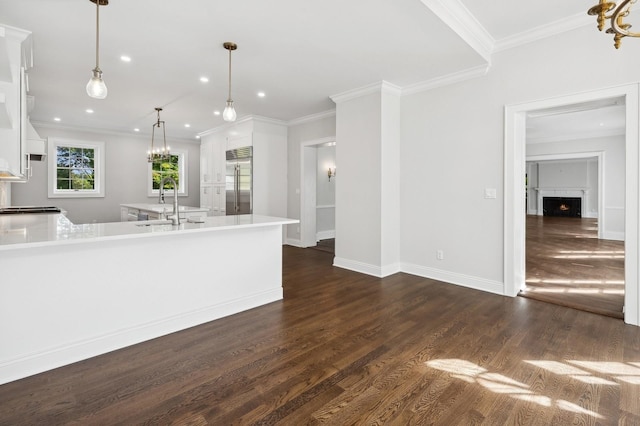 kitchen featuring pendant lighting, dark hardwood / wood-style floors, built in refrigerator, crown molding, and white cabinets