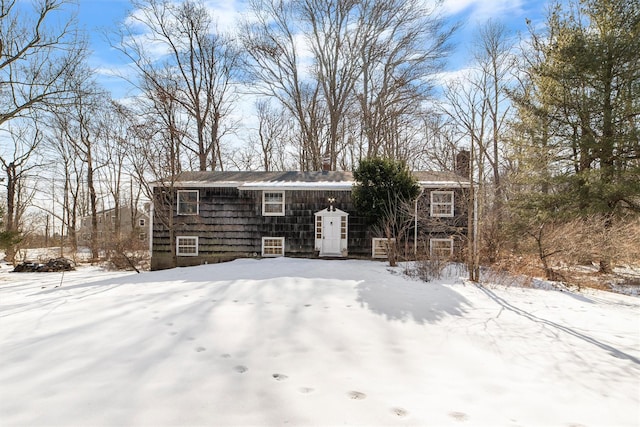 snow covered back of property featuring a chimney