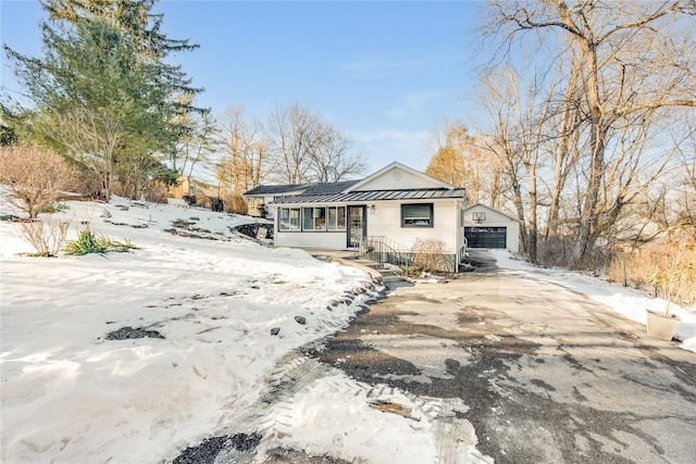 view of front of property with an outbuilding, metal roof, a garage, driveway, and a standing seam roof