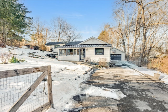 view of front facade featuring an outbuilding, a standing seam roof, a gate, metal roof, and driveway