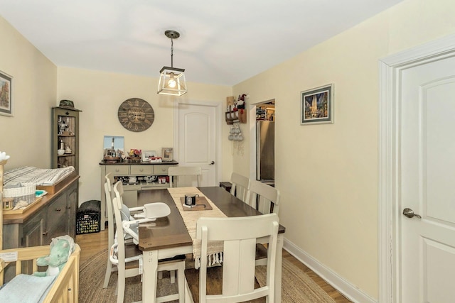 dining space featuring light wood-type flooring and baseboards