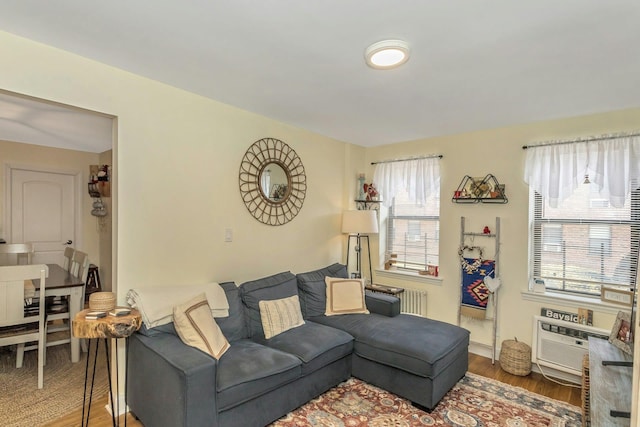 living area with radiator, a wall unit AC, and wood finished floors