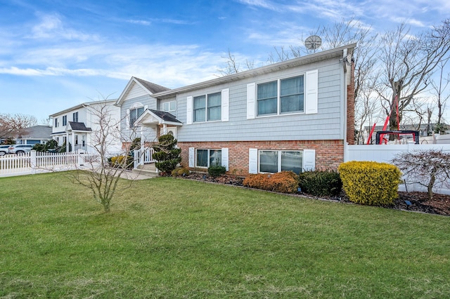 view of front of property with brick siding, fence, and a front lawn