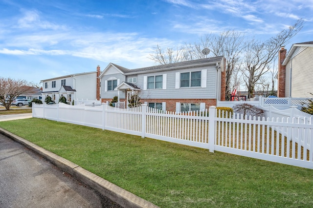 view of front of house featuring a fenced front yard, a front yard, and brick siding