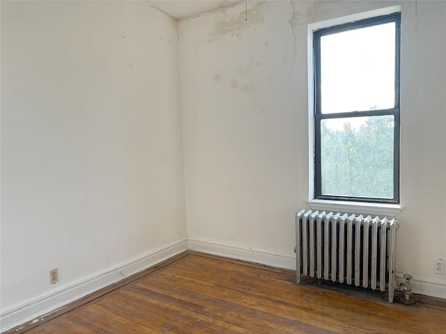 unfurnished room featuring radiator and dark hardwood / wood-style flooring