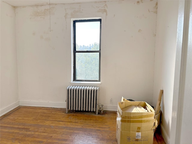 unfurnished room with wood-type flooring and radiator heating unit