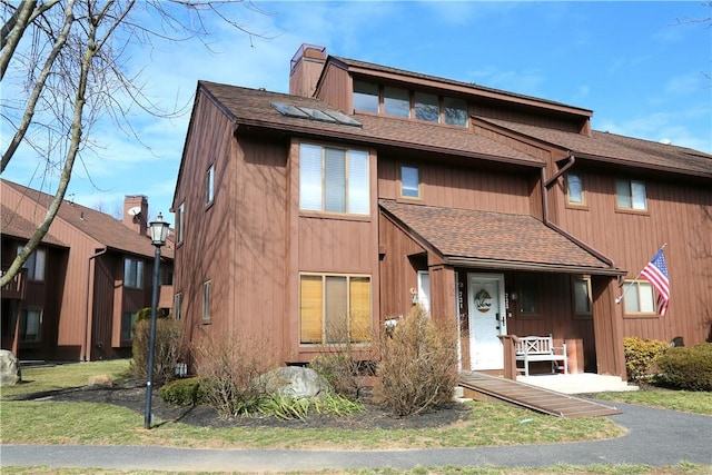 view of property with a chimney and roof with shingles