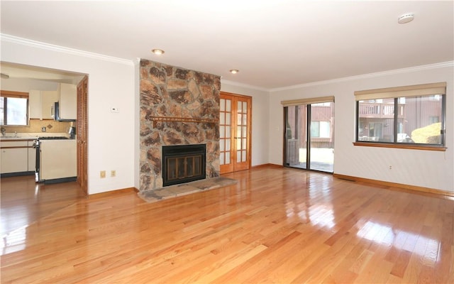 unfurnished living room featuring light wood-style flooring, a fireplace, ornamental molding, and a wealth of natural light