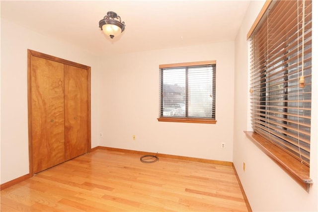 unfurnished bedroom with light wood-style flooring, baseboards, and a closet