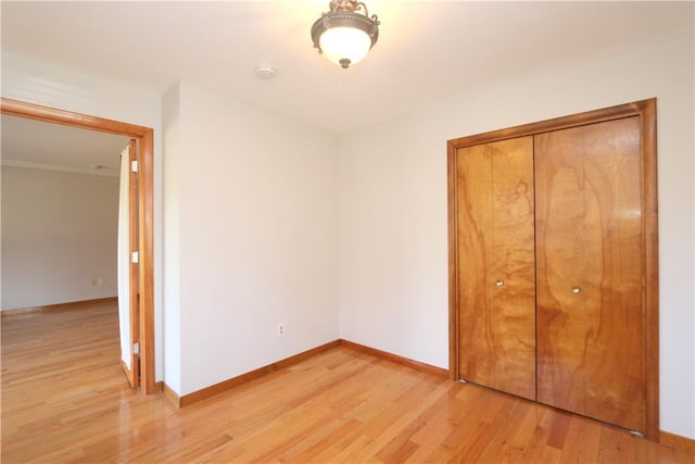 unfurnished bedroom featuring light wood-style floors, a closet, and baseboards