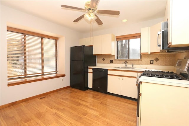 kitchen featuring a sink, black appliances, light countertops, and white cabinets