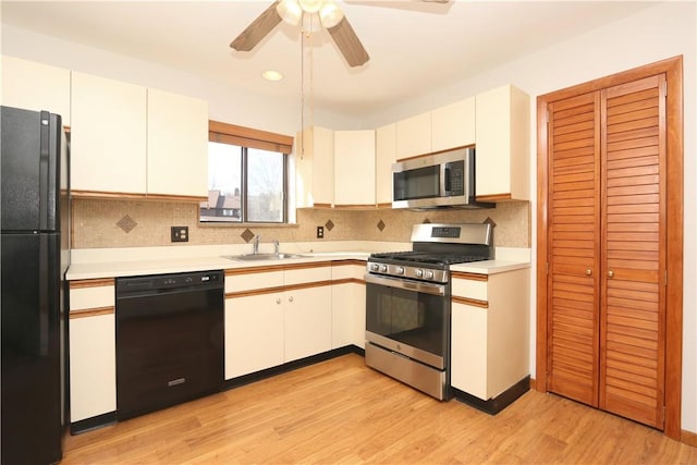 kitchen with light countertops, light wood-style flooring, white cabinetry, a sink, and black appliances