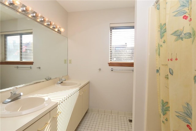 bathroom featuring baseboards, double vanity, a sink, and tile patterned floors