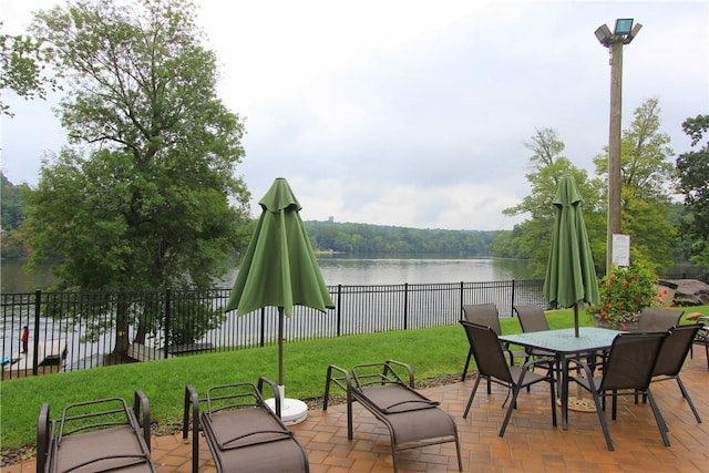 view of patio / terrace featuring outdoor dining space, a water view, and fence