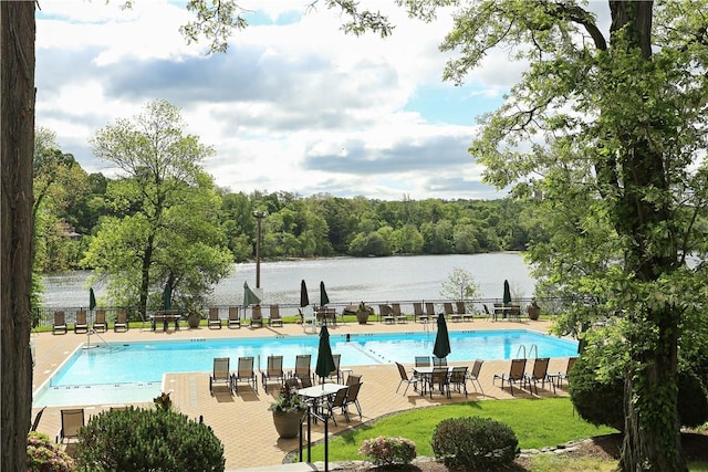 community pool with a patio, a water view, and fence