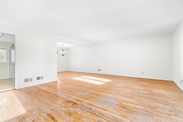 spare room with visible vents, a notable chandelier, and light wood-style flooring