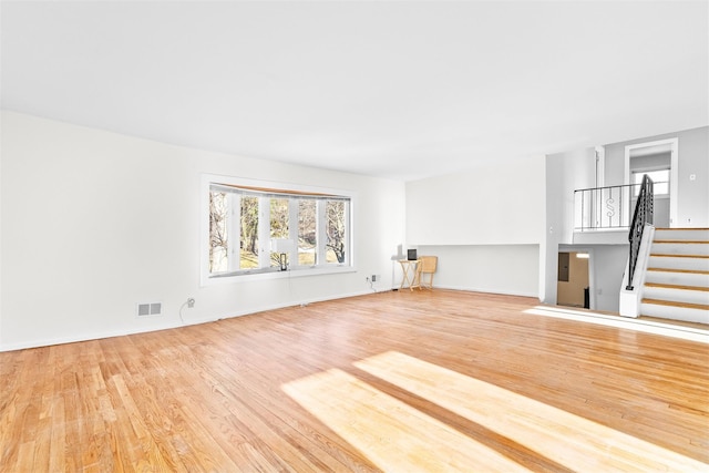 unfurnished living room featuring stairs, visible vents, and wood finished floors