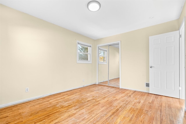 unfurnished bedroom featuring light wood-style floors, baseboards, and a closet