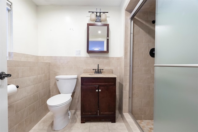 bathroom with toilet, tile patterned floors, vanity, a shower stall, and tile walls