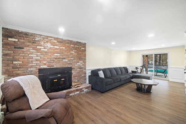 living room featuring a wainscoted wall, a fireplace, a decorative wall, ornamental molding, and wood finished floors