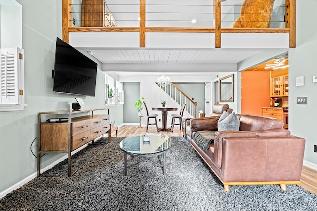 living room with a wealth of natural light, hardwood / wood-style floors, beamed ceiling, and a notable chandelier