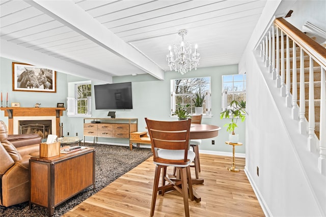 living room featuring beam ceiling, light hardwood / wood-style floors, a chandelier, and wood ceiling