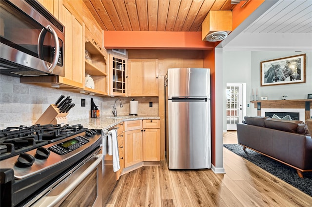 kitchen with sink, light stone counters, stainless steel appliances, light brown cabinetry, and decorative backsplash