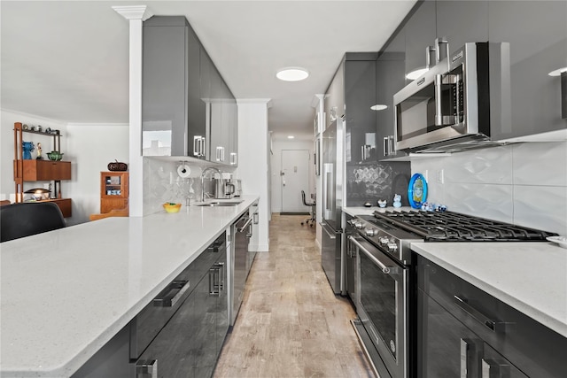 kitchen featuring light hardwood / wood-style flooring, high end appliances, light stone counters, decorative backsplash, and sink