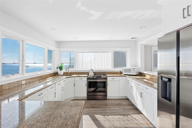 kitchen featuring wood-type flooring, sink, a water view, white cabinetry, and stainless steel appliances