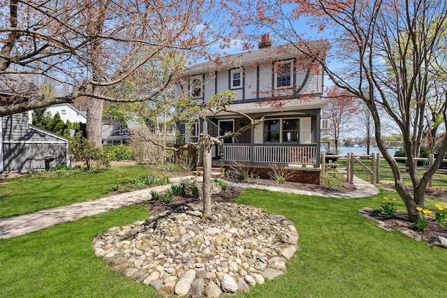 view of front facade featuring stucco siding, covered porch, a front yard, and a chimney