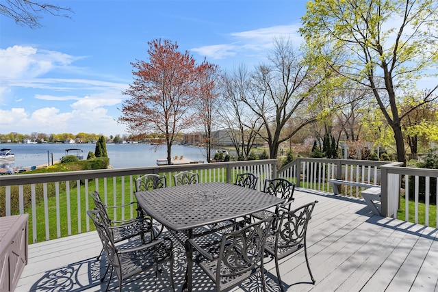 deck with a yard, outdoor dining space, and a water view