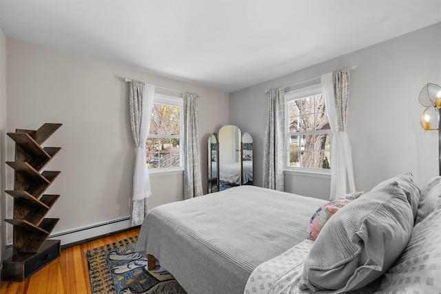 bedroom with wood finished floors and a baseboard radiator
