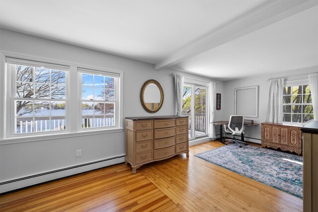 office featuring light wood-style floors, a healthy amount of sunlight, beamed ceiling, and baseboard heating
