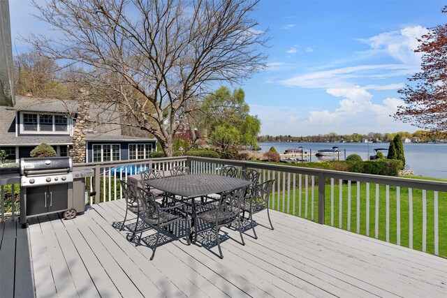 wooden deck with a yard, outdoor dining space, and a water view