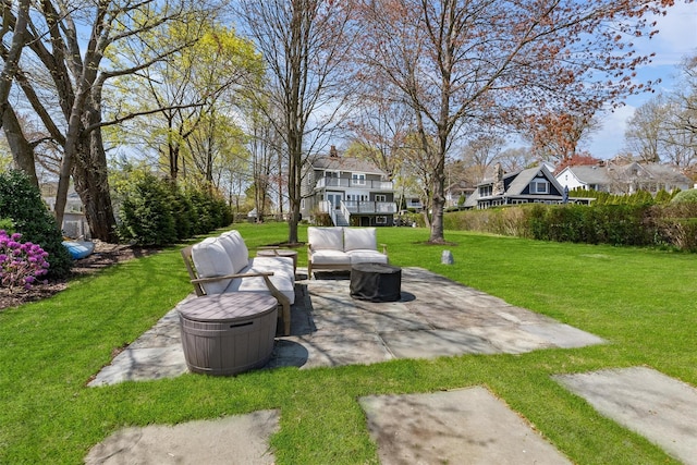 view of yard with an outdoor living space with a fire pit, a patio, and a residential view