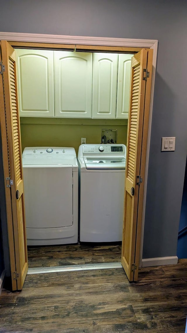 laundry room featuring washer and dryer, baseboards, cabinet space, and dark wood finished floors