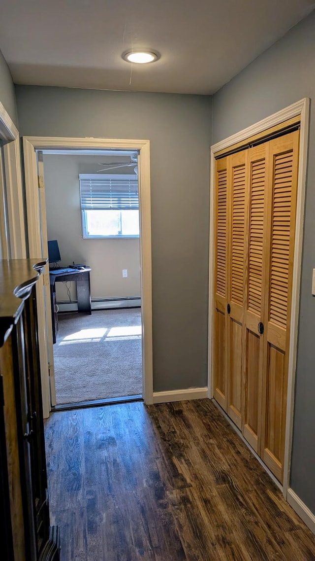 hall featuring dark wood finished floors, baseboards, and a baseboard radiator