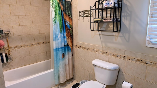 full bathroom featuring shower / bath combo with shower curtain, toilet, tile walls, and wainscoting