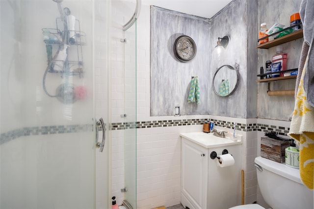 full bath with a stall shower, tile walls, toilet, and vanity