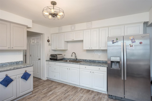kitchen featuring stainless steel refrigerator with ice dispenser, a sink, tasteful backsplash, and white cabinets