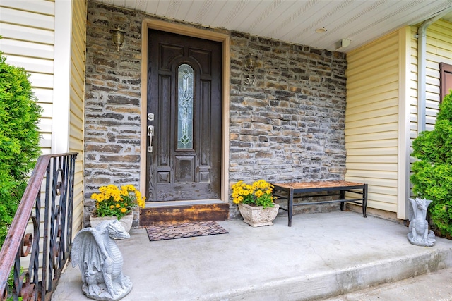 view of exterior entry with stone siding and covered porch