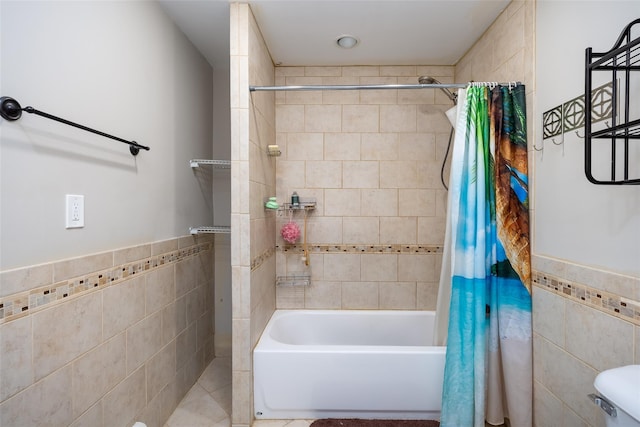 full bathroom featuring tile walls, shower / bathtub combination with curtain, and a wainscoted wall