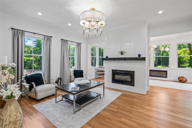 living area featuring a notable chandelier, recessed lighting, a large fireplace, light wood-type flooring, and baseboards