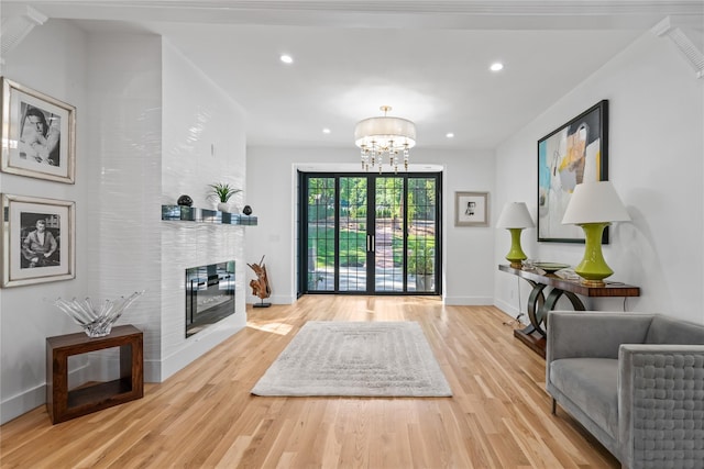 entryway with a large fireplace, baseboards, a notable chandelier, and light wood-style floors