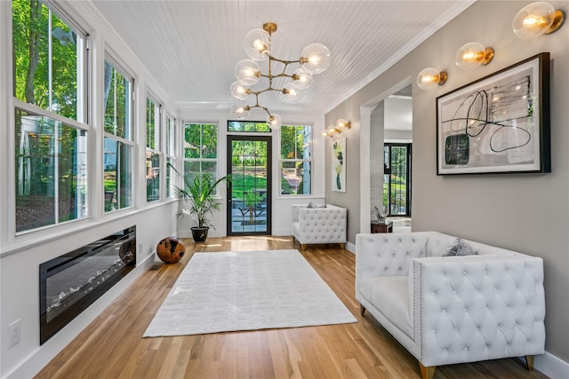 interior space featuring baseboards, a notable chandelier, wood finished floors, and crown molding