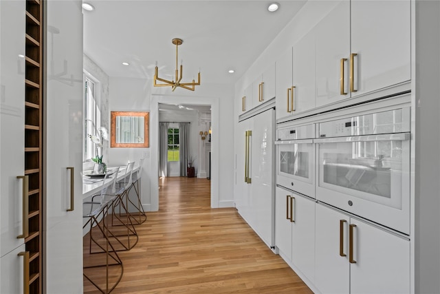 kitchen with recessed lighting, oven, light wood-style floors, white cabinetry, and built in fridge