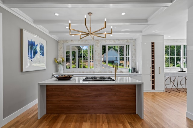 kitchen featuring stainless steel gas cooktop, beamed ceiling, a wealth of natural light, and light wood-style floors