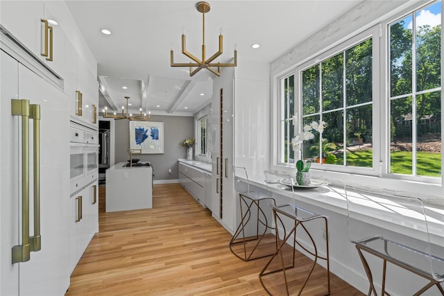 kitchen with modern cabinets, an inviting chandelier, light wood-type flooring, white cabinetry, and built in fridge