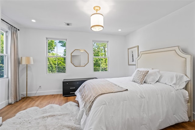 bedroom with recessed lighting, wood finished floors, visible vents, and baseboards